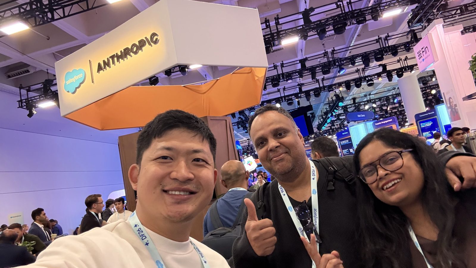 Kevin Bai with two attendees under the Anthropic sign at the booth